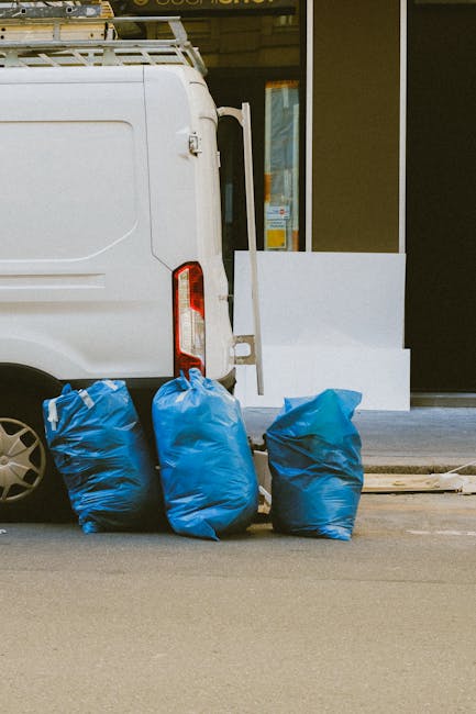 The image shows the rear section of a white commercial van parked on a street, with three large blue rubbish bags placed upright on the pavement just behind the vehicle. The bags appear to be made of 